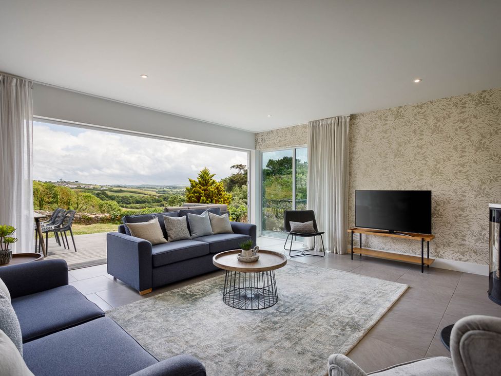 A living room with a sofa and coffee table at Whalesborough Cottage Spa in Marhamchurch