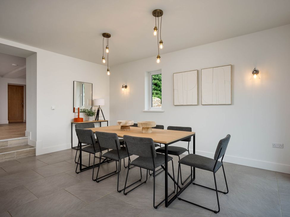 A dining room with a table and chairs at Whalesborough Cottage Spa Marhamchurch