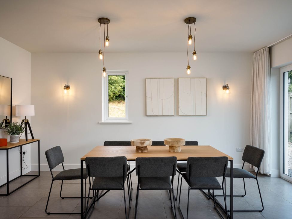 A dining room with a table and chairs at Whalesborough Cottage Spa in Marhamchurch