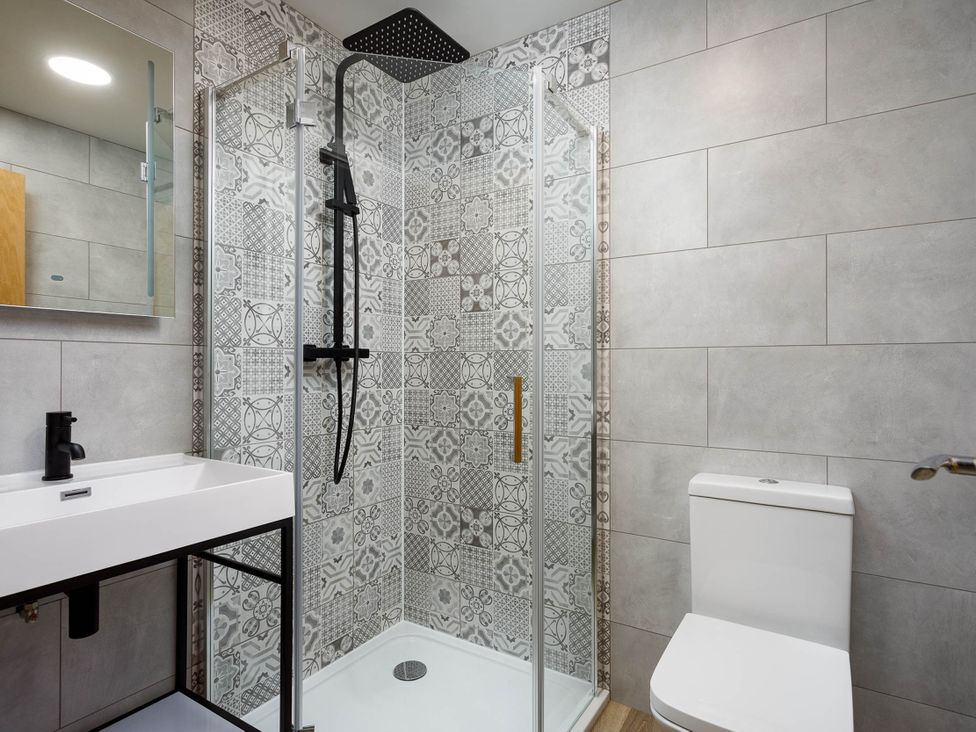 A bathroom with shower, toilet, and sink at Whalesborough Cottage Spa in Marhamchurch