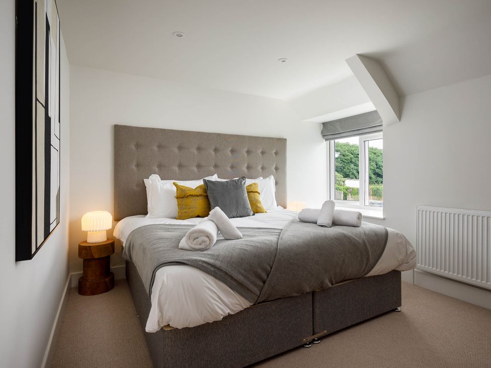 A bedroom with a bed and bedside lamps at Whalesborough Cottage Spa in Marhamchurch