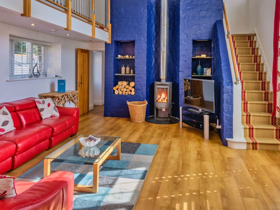 A living room with a fireplace and television at Calf House Spa Marhamchurch