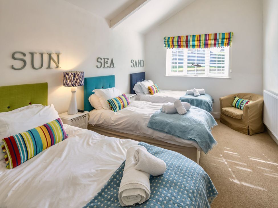 A bedroom with three beds and a chair at Calf House Spa in Marhamchurch