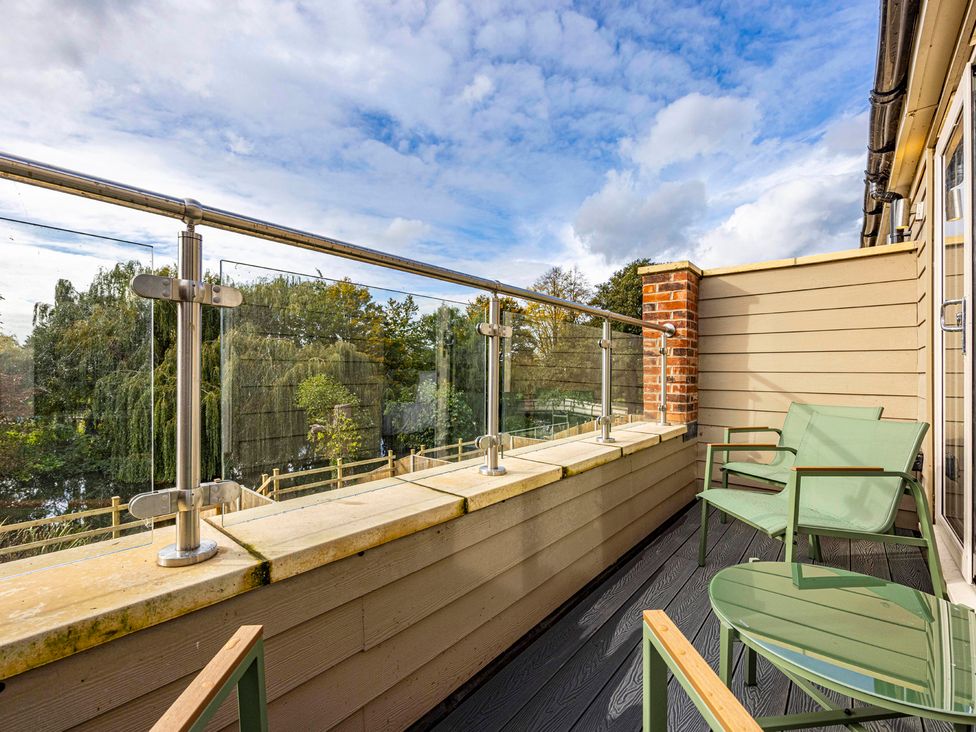 A balcony with green chairs and a glass railing at 7 Riverside Mews Derby