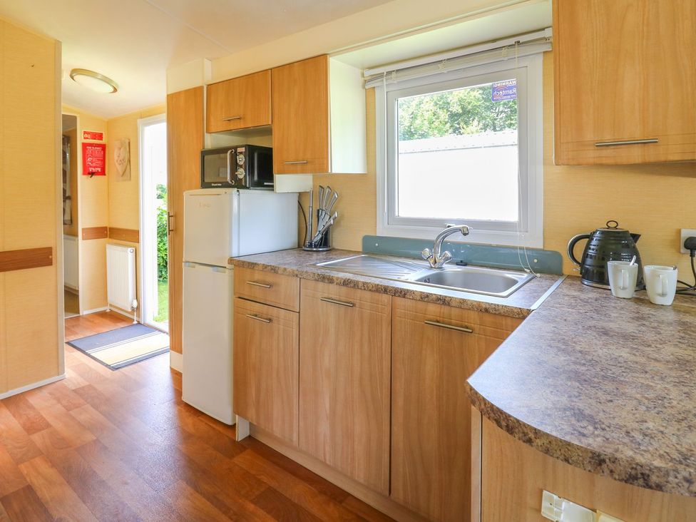 A kitchen with a fridge, microwave, sink, and countertop at Caravan 2 at Blackmoor Farm near tenby