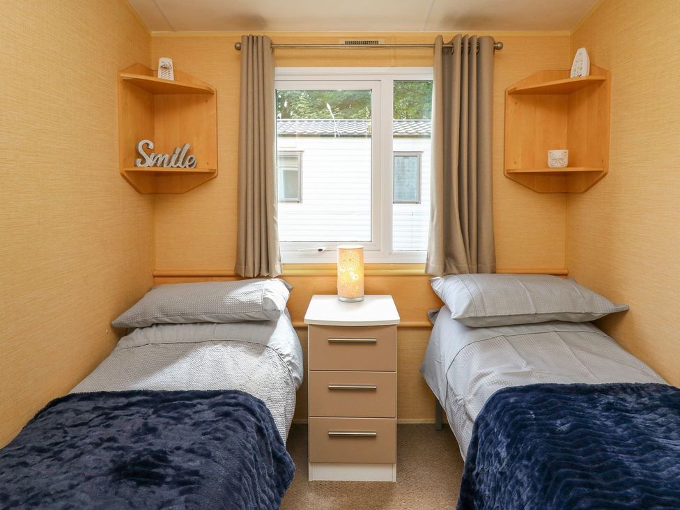 A bedroom with two beds and a nightstand at Caravan 2 at Blackmoor Farm near tenby