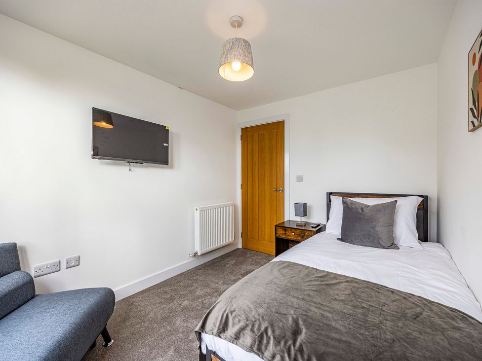A bedroom with a bed, TV, and sofa at 8 Riverside Mews in Derby