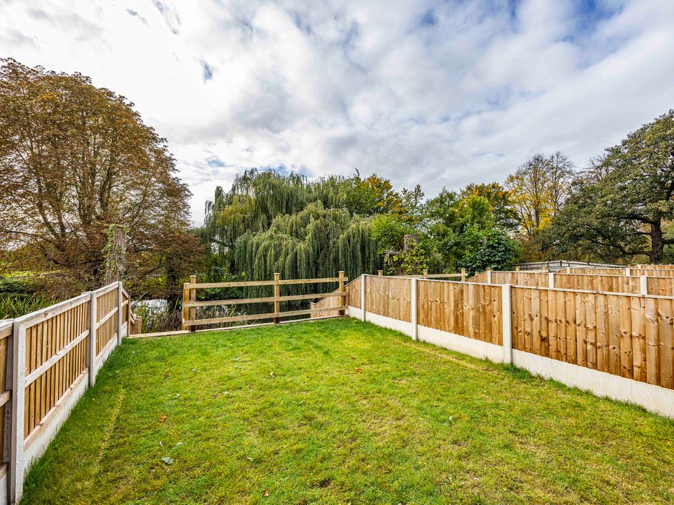 A garden with a fence and trees at 8 Riverside Mews in Derby