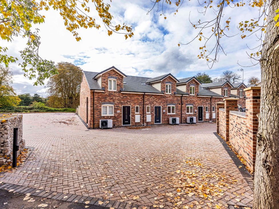 A row of houses with a paved driveway and trees at 8 Riverside Mews in Derby