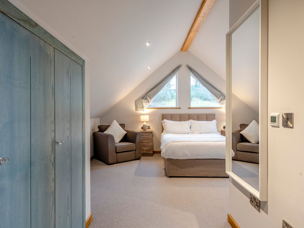 A bedroom with a bed and armchairs at Tranquillity 4 in Carnforth