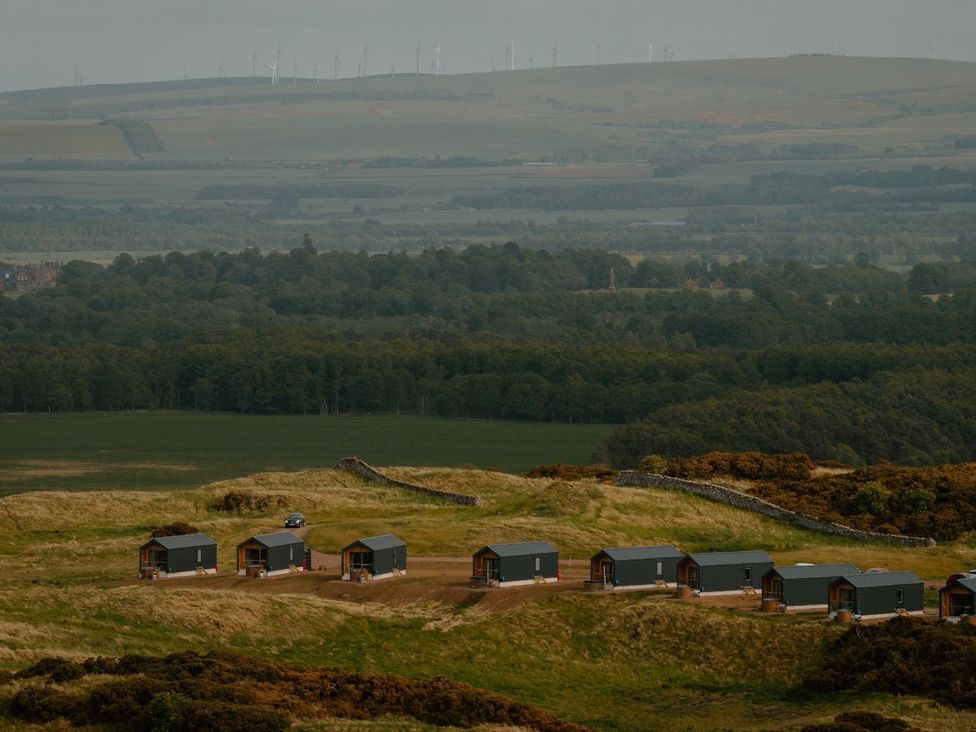A landscape with cabins, a car, and wind turbines at The Laidlaw Spa in North Berwick