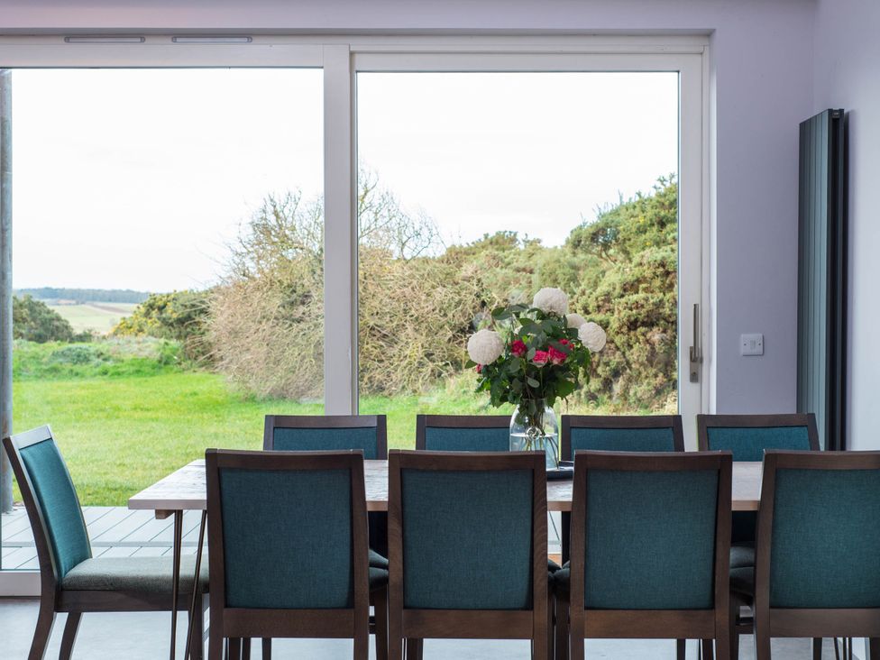 A dining room with a table and chairs overlooking a green outdoor area at The Laidlaw in North Berwick