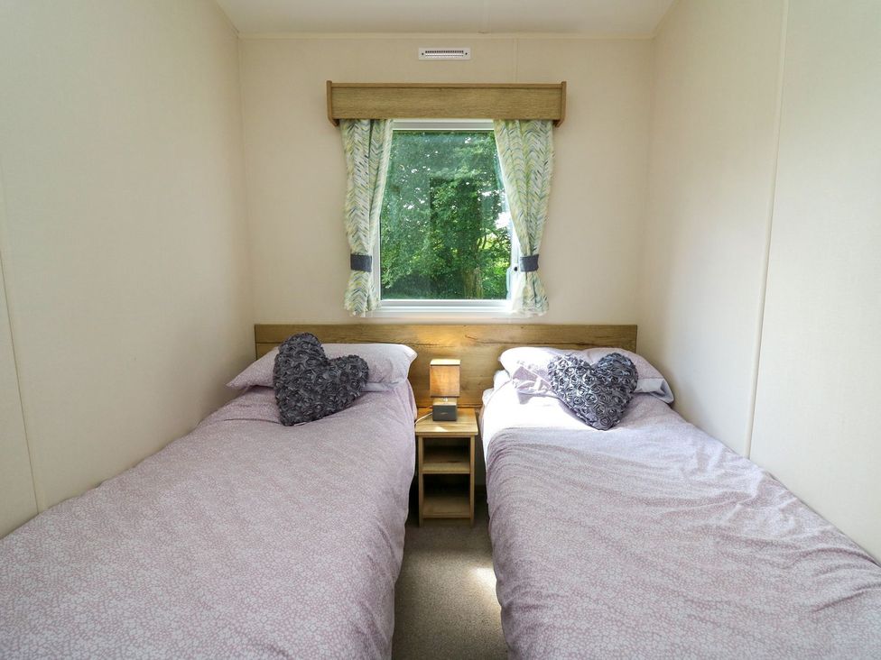 A bedroom with two single beds and a window at Caravan 6 at Blackmoor Farm near tenby