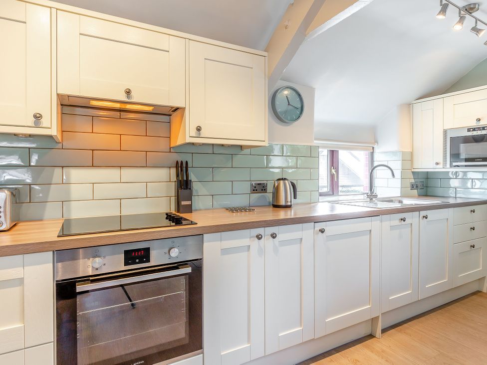 A kitchen with units, oven, and sink at Crabtree Cottage in Bude