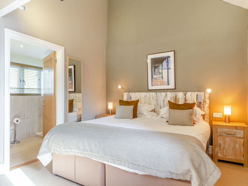 A bedroom with a double bed and connected bathroom at Godolphin Stable, Bude