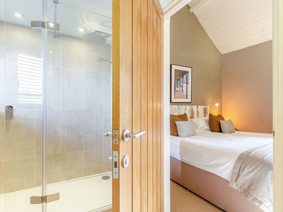 A bathroom with a shower and a bedroom with a bed at Godolphin Stable in Bude