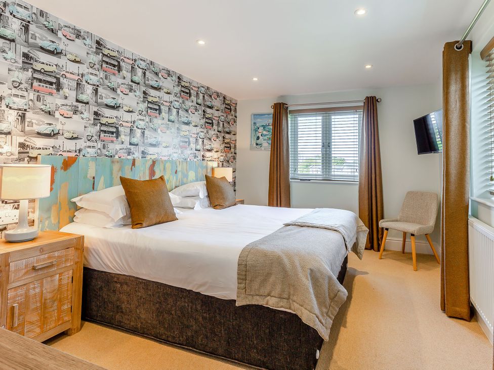 A bedroom with a bed and window at Godolphin Stable in Bude