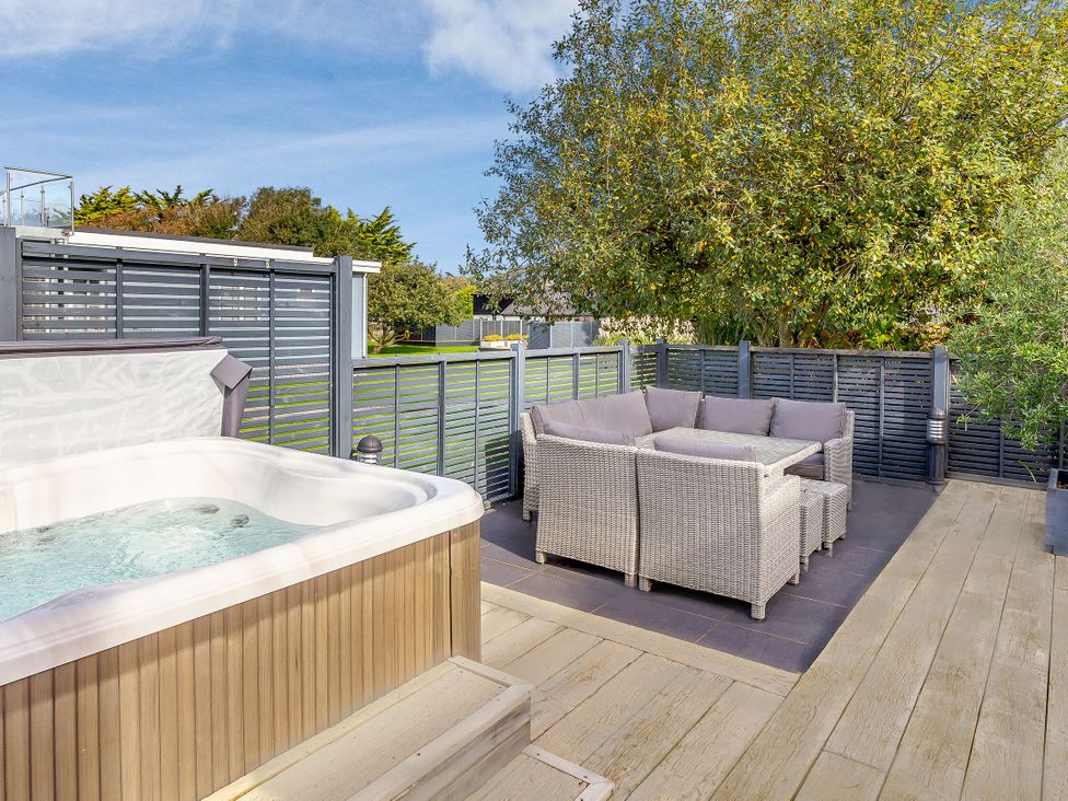 An outdoor area with a hot tub and seating at Godolphin Stable Bude