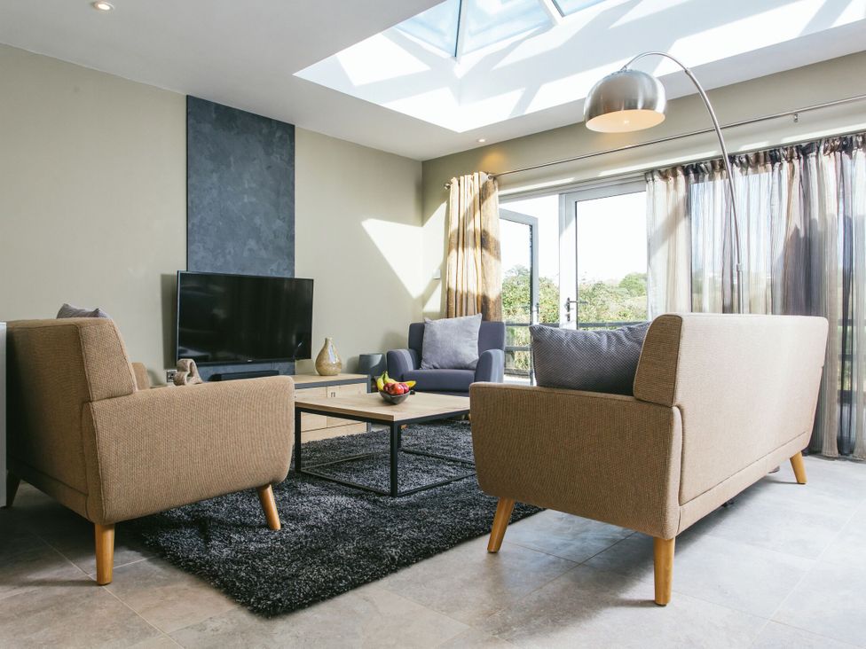 A living room with a sofa and television at Cornish Lodge Spa in Bude