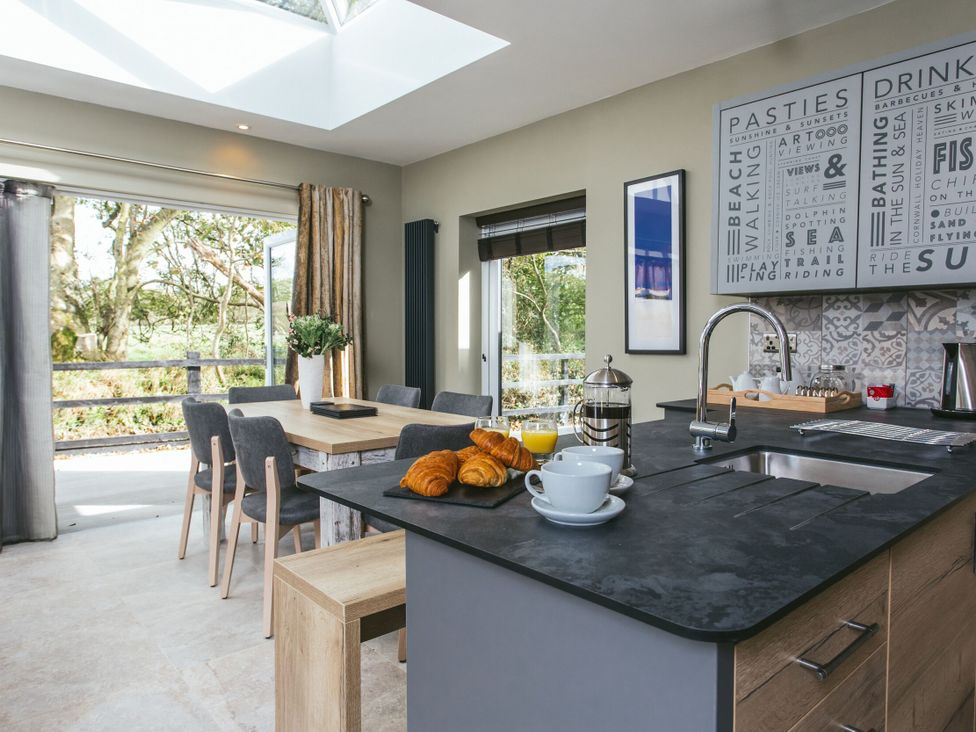 A kitchen with a table and chairs, coffee and croissants at Cornish Lodge Spa in Bude