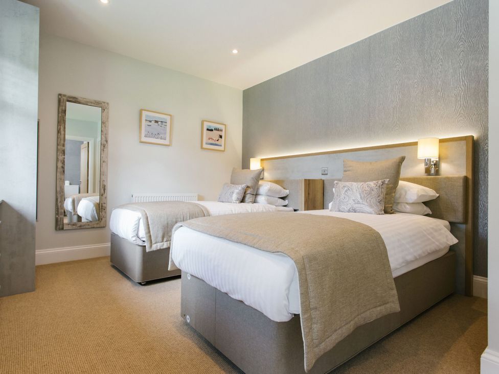 A bedroom with two beds and a mirror at Cornish Lodge Spa in Bude