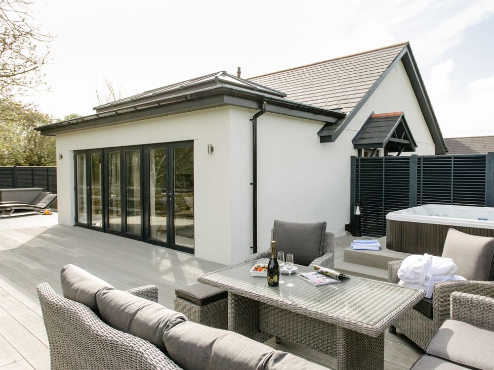 An outdoor area with a hot tub and seating at Cornish Lodge Spa in Bude
