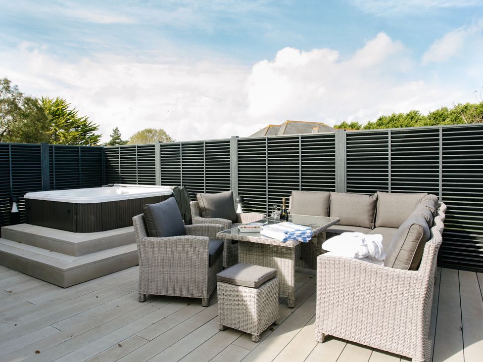 An outdoor area with a hot tub and seating at Cornish Lodge Spa Bude