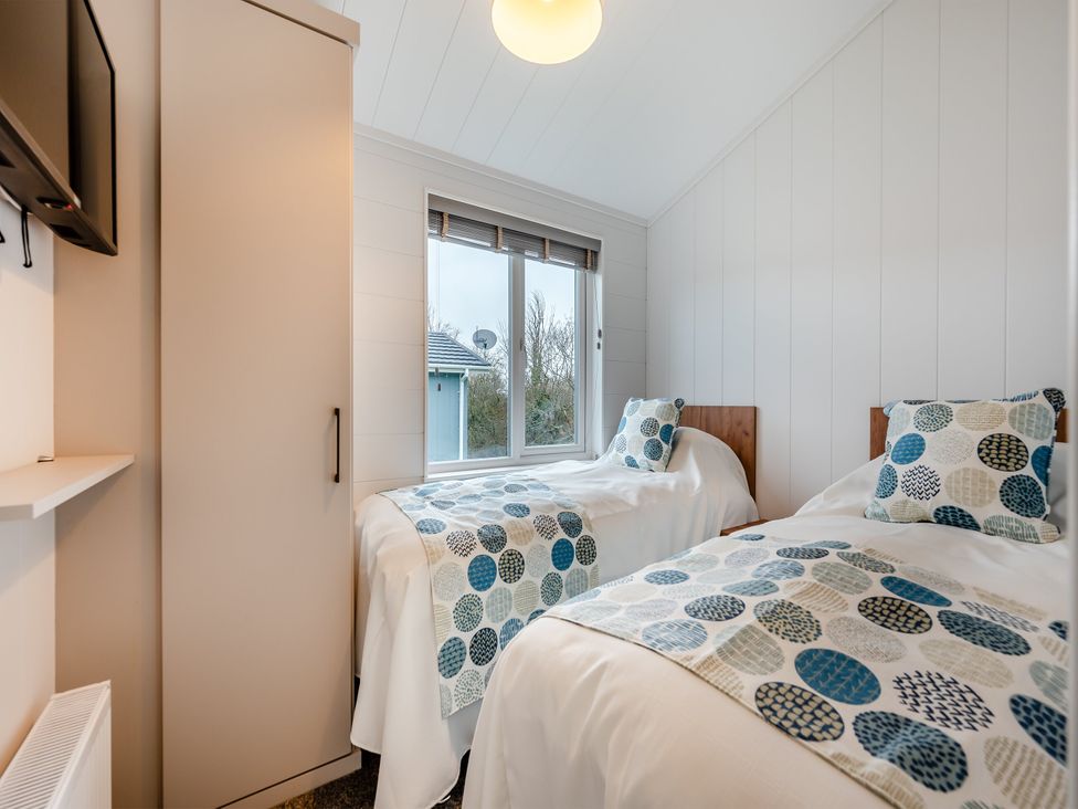 A bedroom with two single beds and a wardrobe at Kynance Spa (Pet) Bude