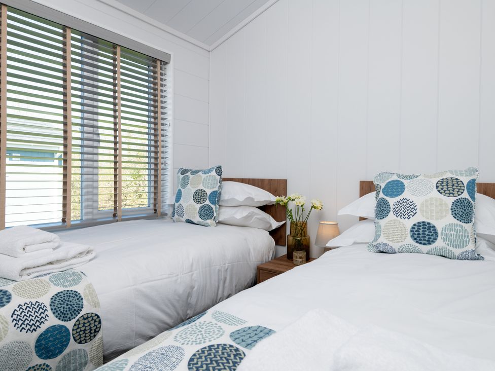 A bedroom with two beds and a window with blinds at Kynance Spa in Bude