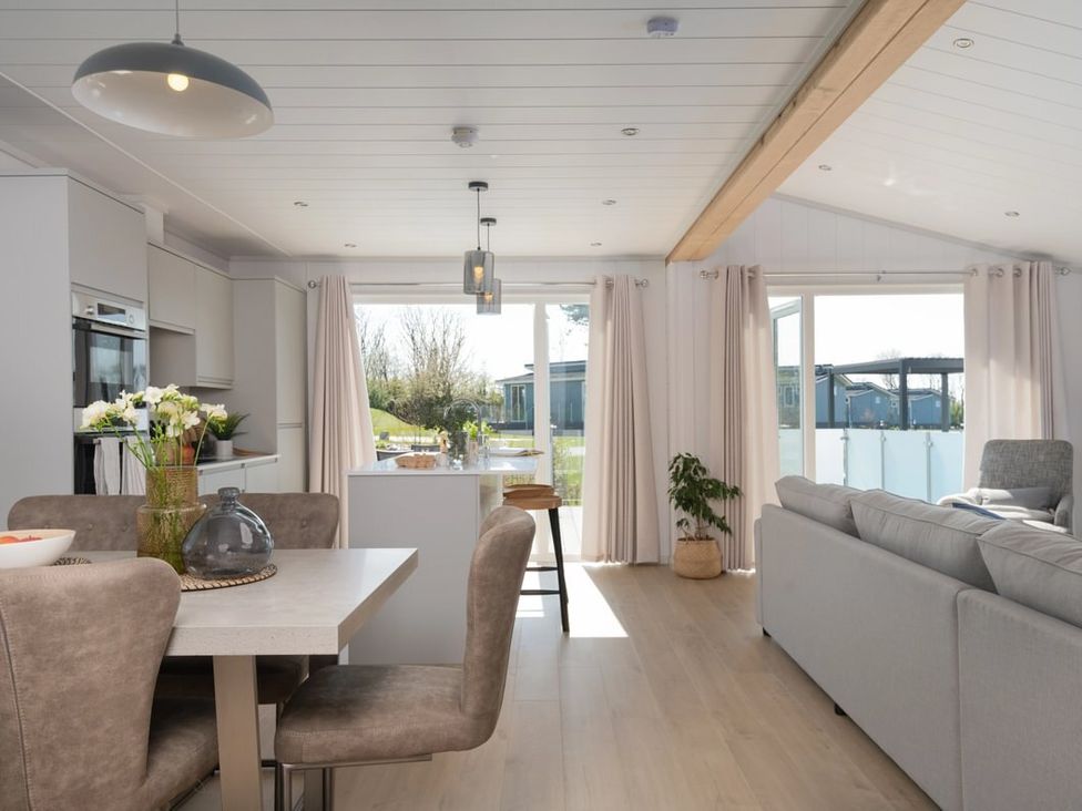 A living room with a dining area and kitchen cabinets at Sennen 2 Spa Roof Terrace (Pet) in Bude