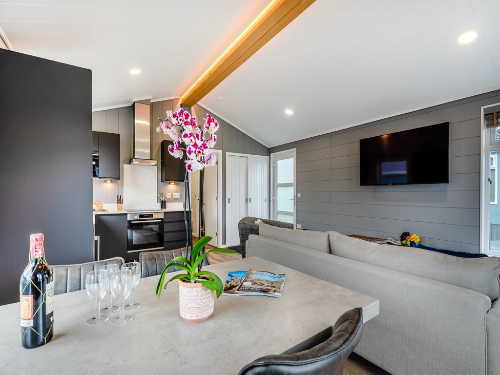 A living room with a dining table and kitchen area at Kynance (Pet) in Bude