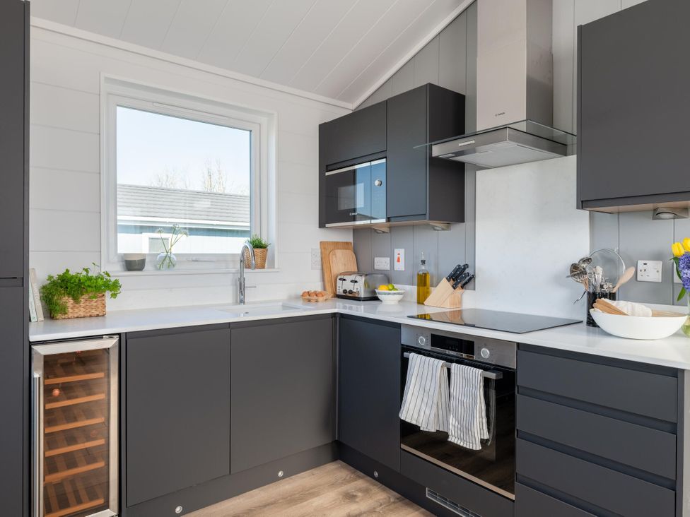 A kitchen with a sink, countertop, and appliances at Kynance (Pet) Bude