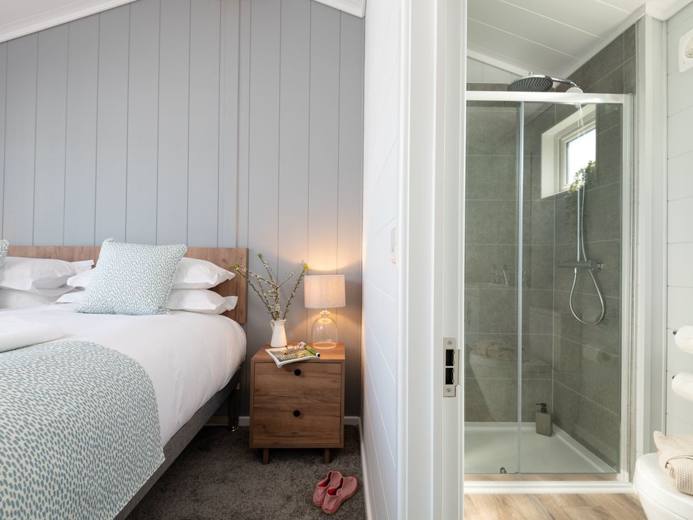 A bedroom with a bed and a shower area at Kynance (Pet) Bude