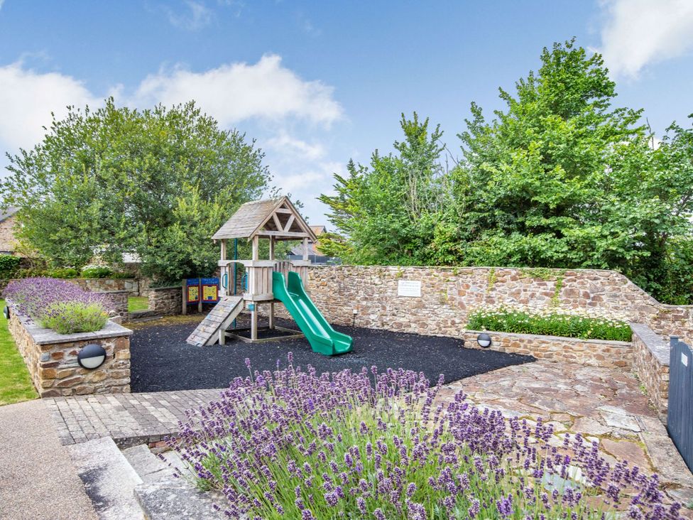 An outdoor playground with a slide and playhouse at Kynance (Pet) Bude