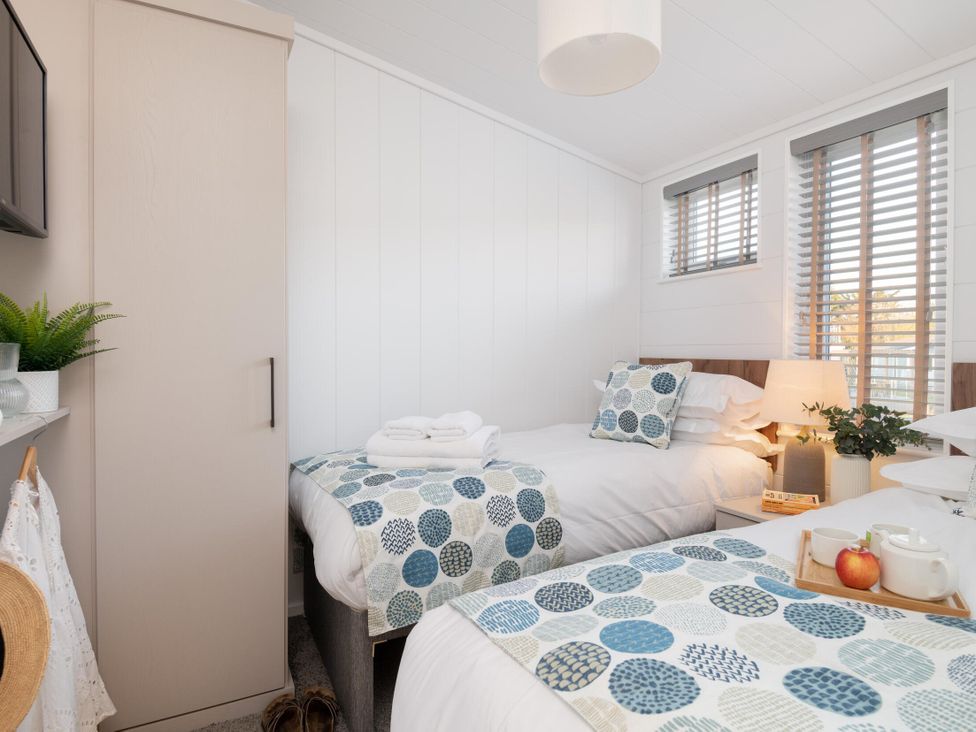A bedroom with two beds and a wardrobe at Mullion 2 Spa (Pet) in Bude