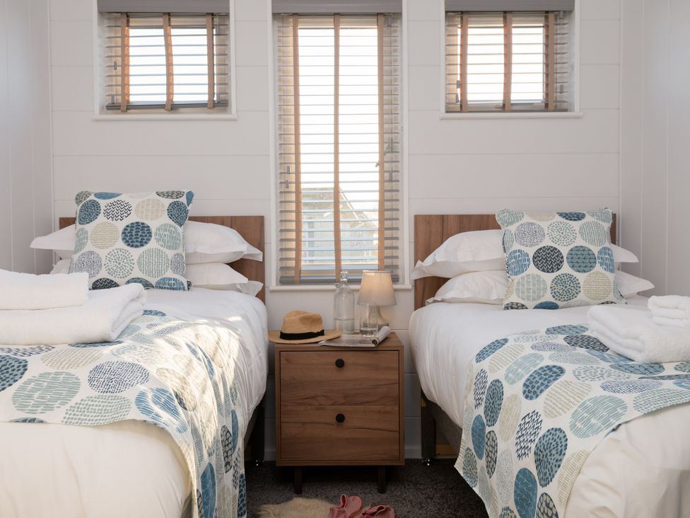 A bedroom with two beds and a bedside table at Mullion 2 Spa (Pet) Bude