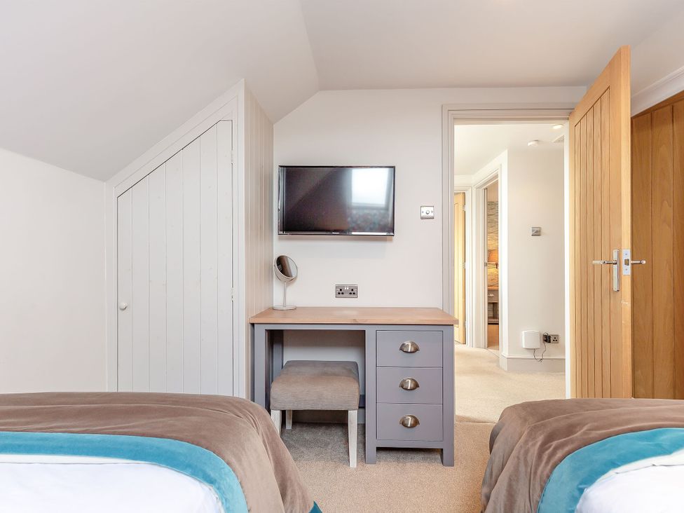 A bedroom with a desk and television at Summerleaze Garden Cottage 3 Spa in Bude