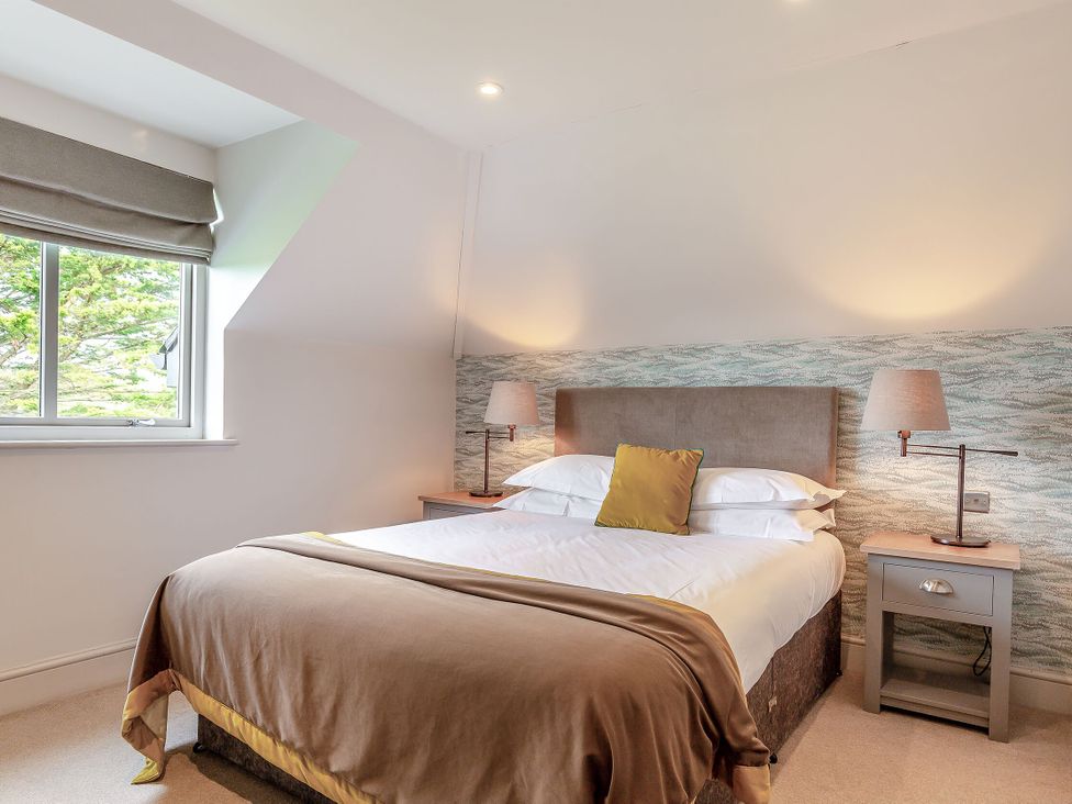 A bedroom with a bed and side tables at Summerleaze Garden Cottage 3 Spa in Bude