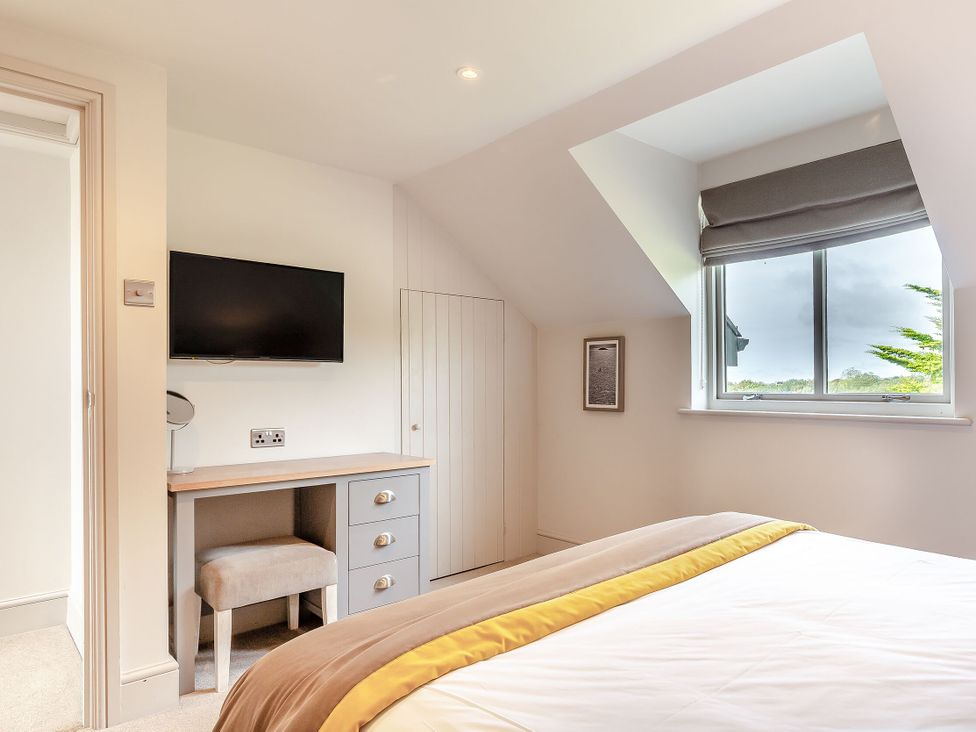A bedroom with a bed, desk, chair, and television at Summerleaze Garden Cottage 3 Spa Bude