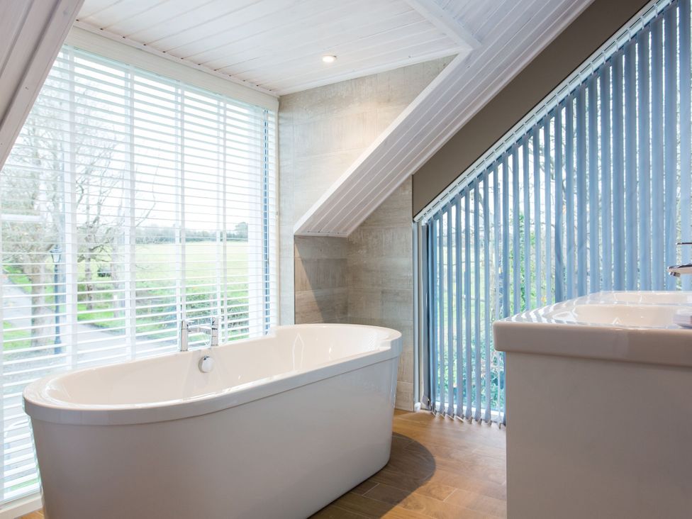 A bathroom with a bathtub and sink at The Glasshouse in Bude