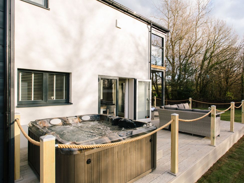 An outdoor area with a hot tub and seating at The Glasshouse in Bude