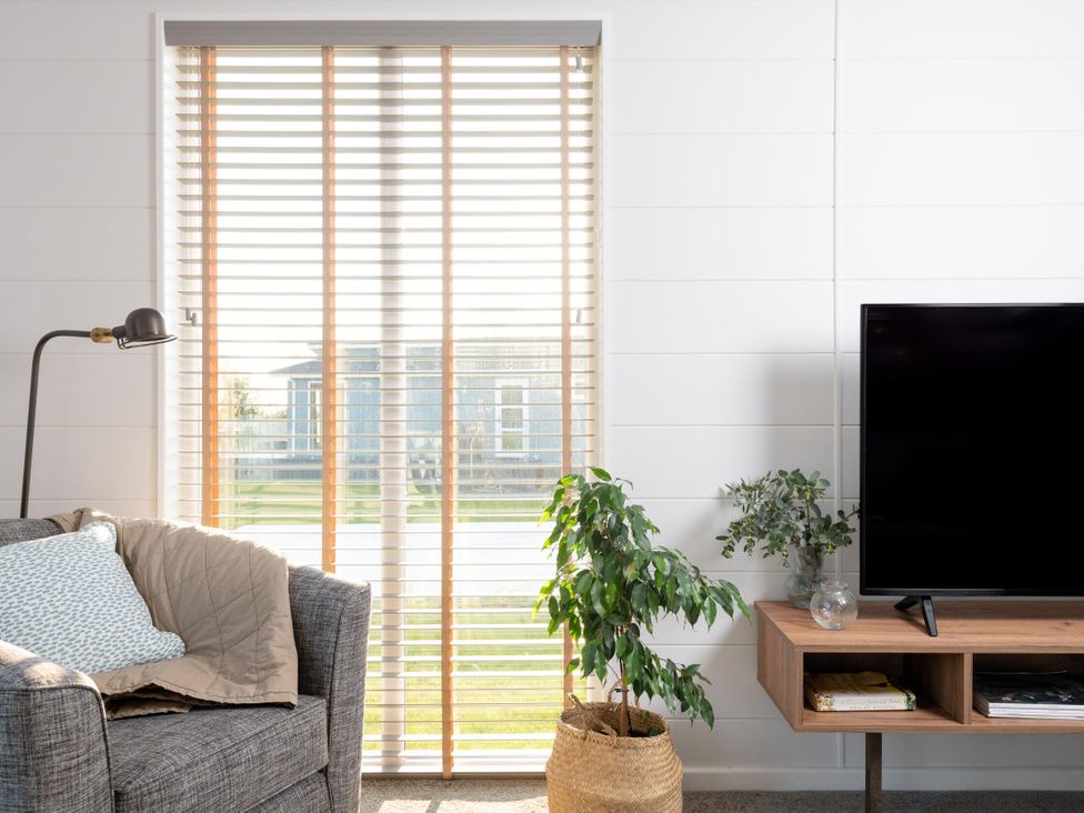 A living room with a sofa, lamp, and television at Mullion Spa (Pet) in Bude