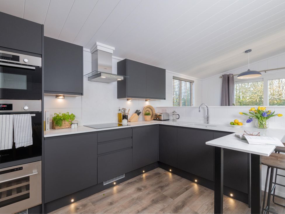 A kitchen with modern appliances and a table at Mullion Spa (Pet) Bude