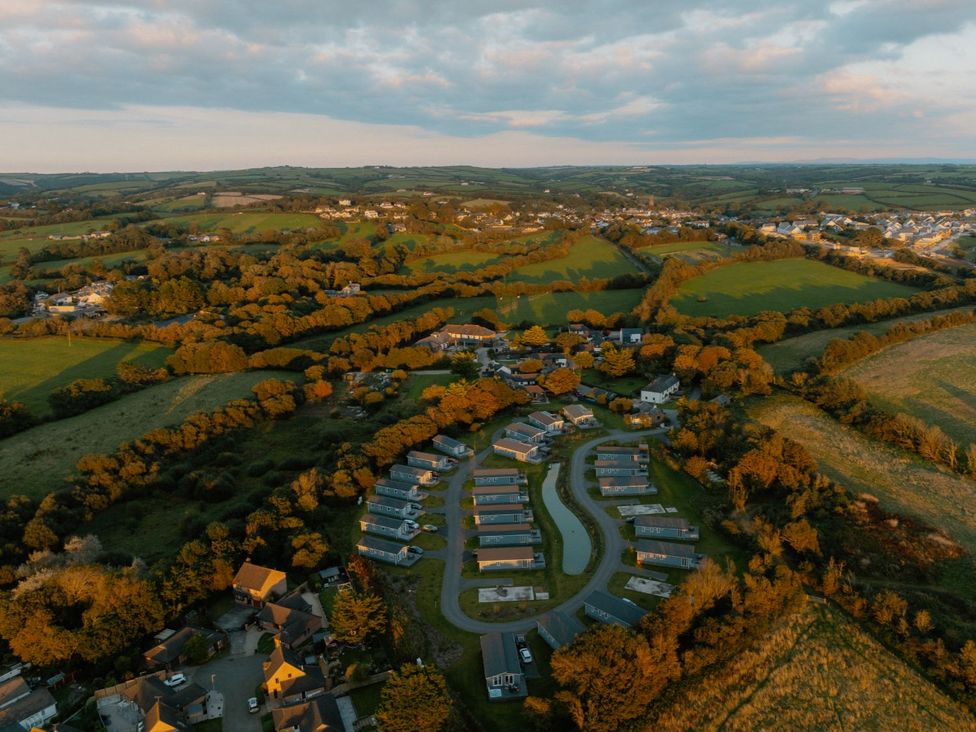 An aerial view of a caravan park surrounded by fields and trees at Mullion Spa (Pet) Bude