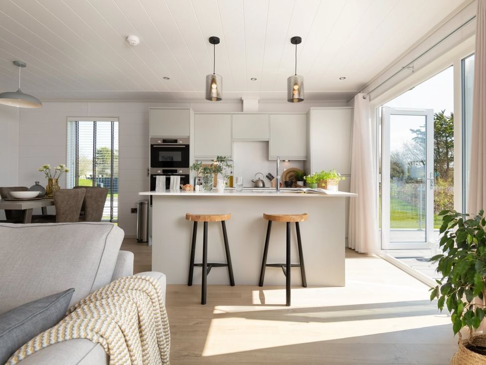 A kitchen with stools and an island at Sennen 3 Spa Roof Terrace (Pet) Bude