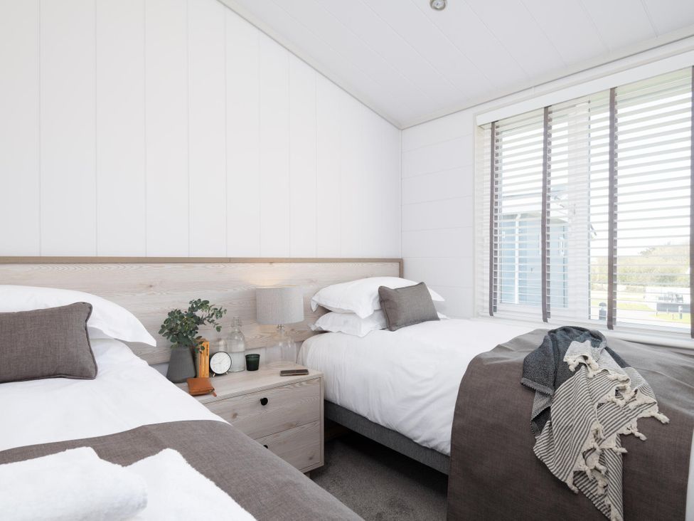 A bedroom with two beds and a bedside table at Sennen 3 Spa Roof Terrace (Pet) in Bude