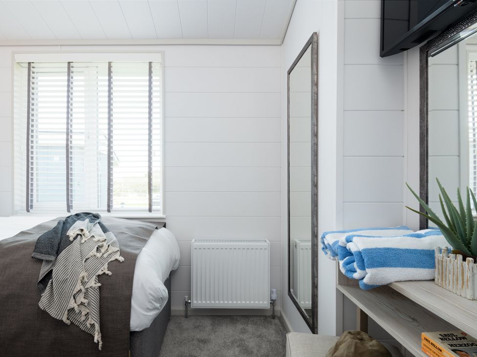 A bedroom with a bed and towels on a shelf at Sennen 3 Spa Roof Terrace in Bude