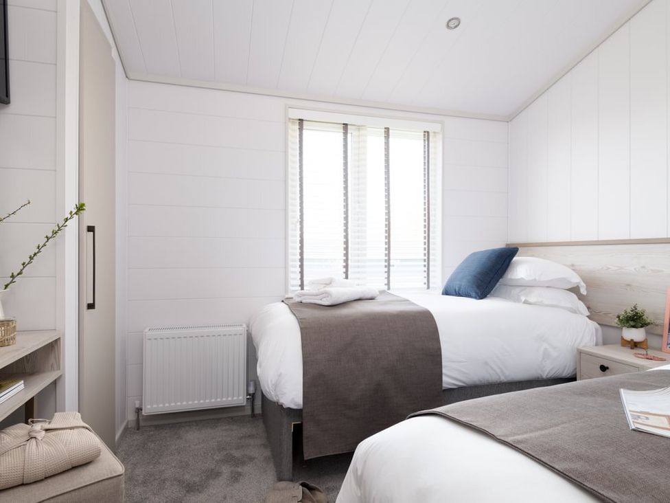 A bedroom with two beds and a nightstand at Sennen 3 Spa (Pet) Bude