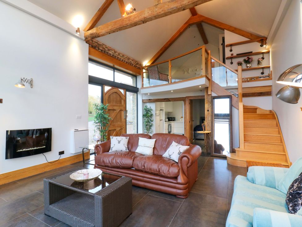 A living room with a sofa, coffee table, and stairs at The Lodge @ Lodge Farm in Bedford