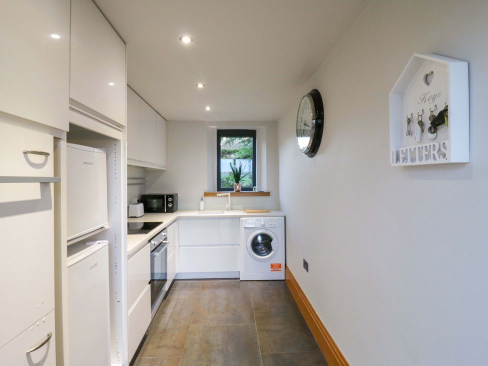 A kitchen with a washing machine and refrigerator at The Lodge @ Lodge Farm Bedford